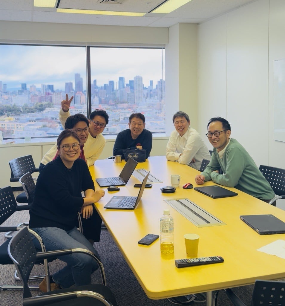 A group of people sitting around a table with laptops

Description automatically generated